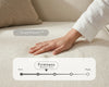 Close-up of a hand testing the soft cream upholstered sofa seat, showcasing SmartFoam™ comfort and medium-firm support in a modern living room.