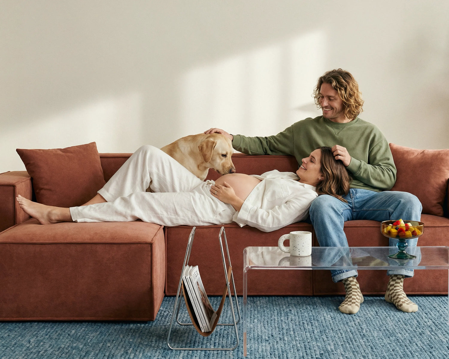 Couple relaxing with a dog on a rust upholstered modular sofa, showcasing soft fabric, spacious seating, pet-friendly comfort, and cosy living room lounging.